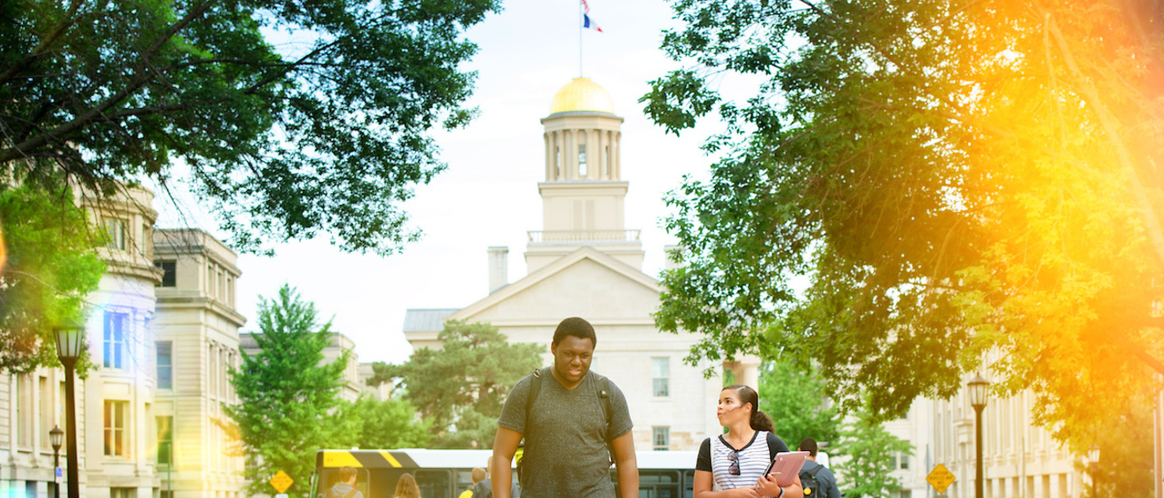 Students walk on T. Anne Cleary Walkway with Old Capitol in background