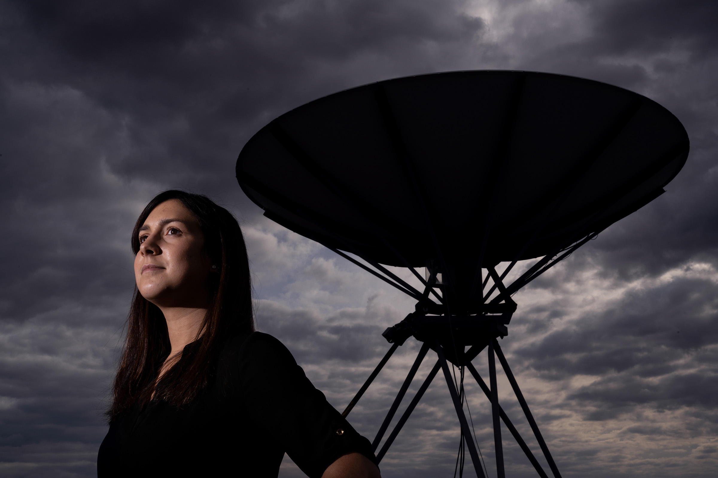 UI Grad Emily Silich looks to the sky while standing in front of a massive satellite dish