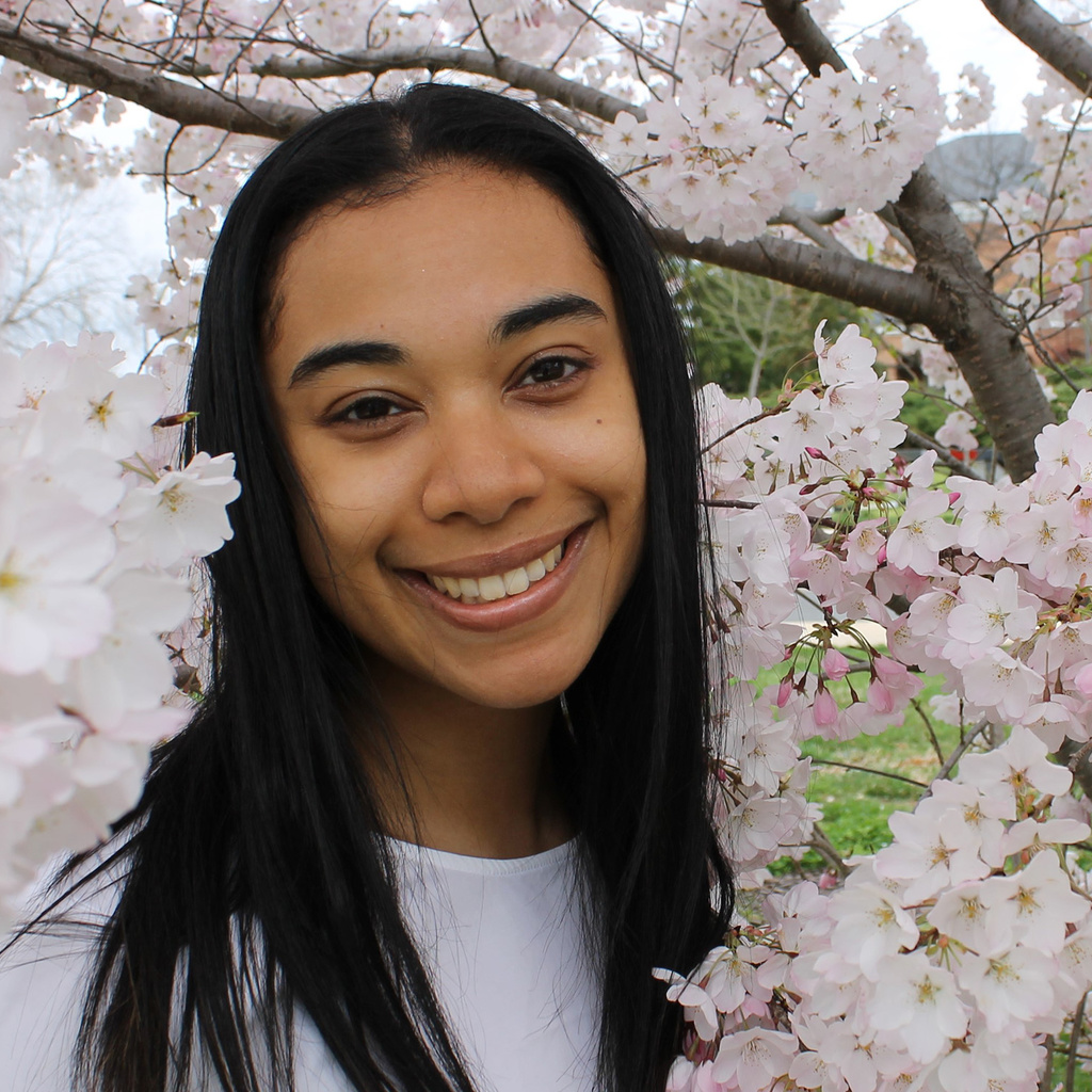 Carson Peters smiles for photo in front of a cherry blossom tree
