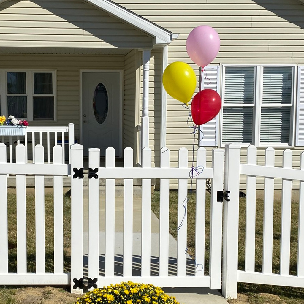 House with balloons tied to white picket fence