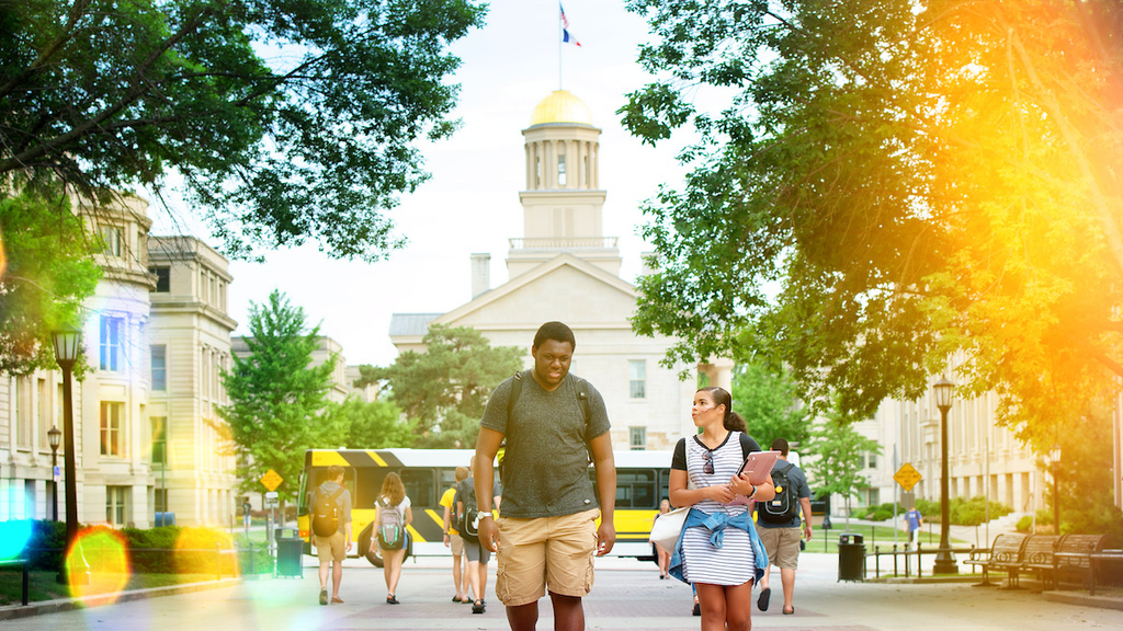 Students walk on T. Anne Cleary Walkway with Old Capitol in background