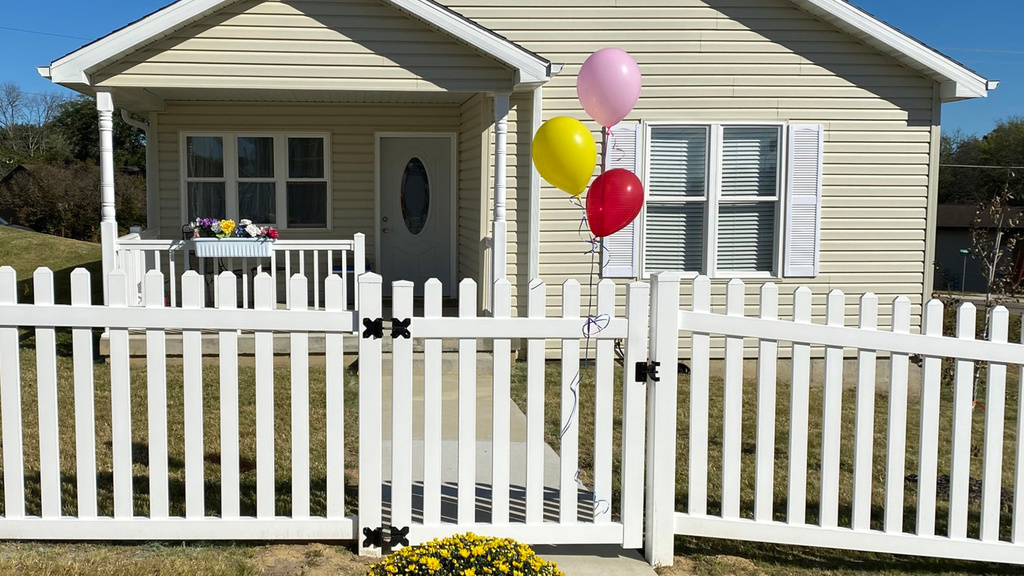 House with balloons tied to white picket fence